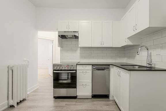 A modern kitchen with white cabinets and a black countertop. at 723 Bloor Apartments, Canada
