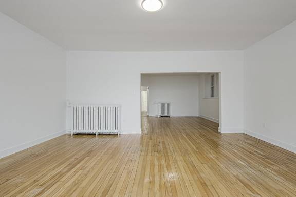A room with wooden floors and two radiators. at 723 Bloor Apartments, Canada, M6G 1L5