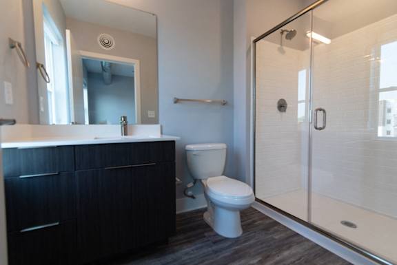 A bathroom with a toilet, sink, and mirror.