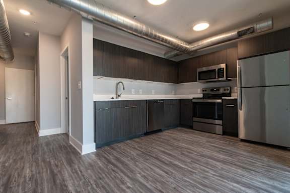 A modern kitchen with stainless steel appliances and wooden flooring.