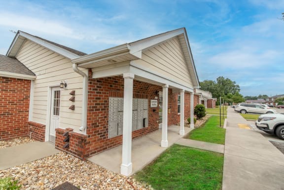a brick and white building with a sidewalk in front of it and a parking lot in the