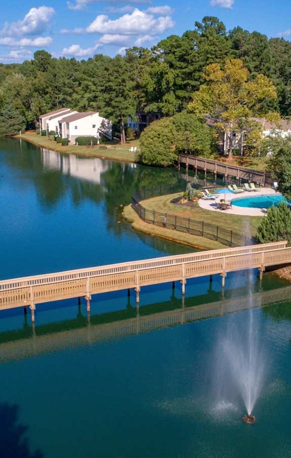 A fountain in the middle of a lake with a bridge leading to a pool.