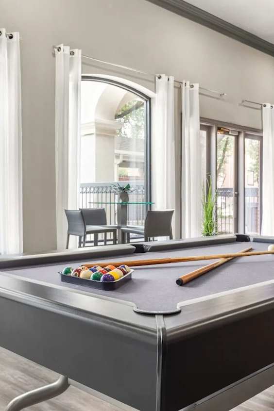 A pool table in a room with a view of the street outside.