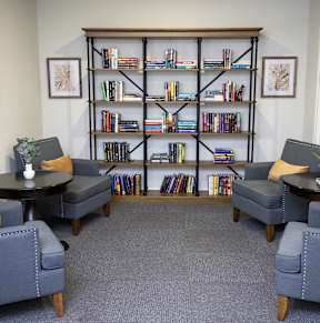 A room with a bookshelf and four chairs.
