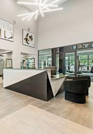A black and white abstract painting hangs on a white wall in a modern office lobby.
