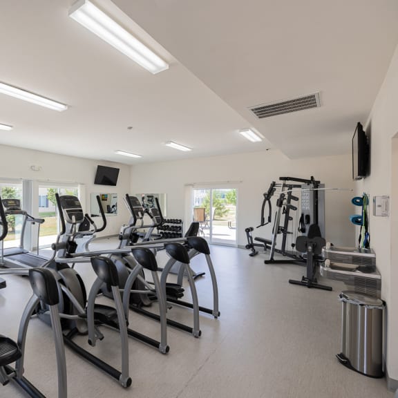a gym with cardio equipment and weights on the floor
