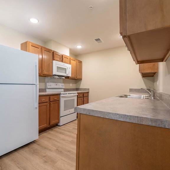 A kitchen with a white fridge and wooden cabinets.