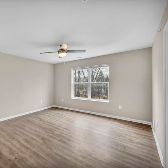 an empty living room with a ceiling fan and a window