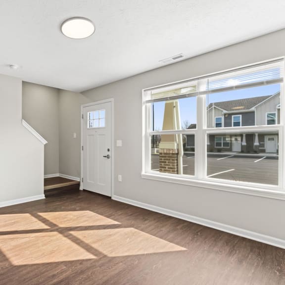 a living room with a large window and hardwood floors