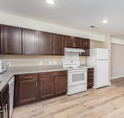 A kitchen with white appliances and wooden cabinets.