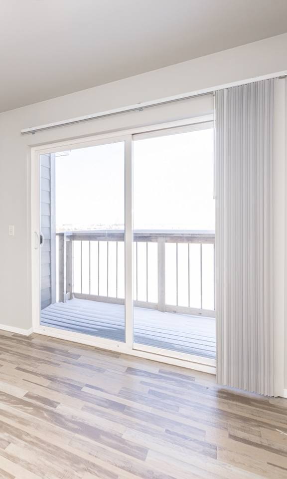 A room with a wooden floor and a sliding glass door leading to a balcony.