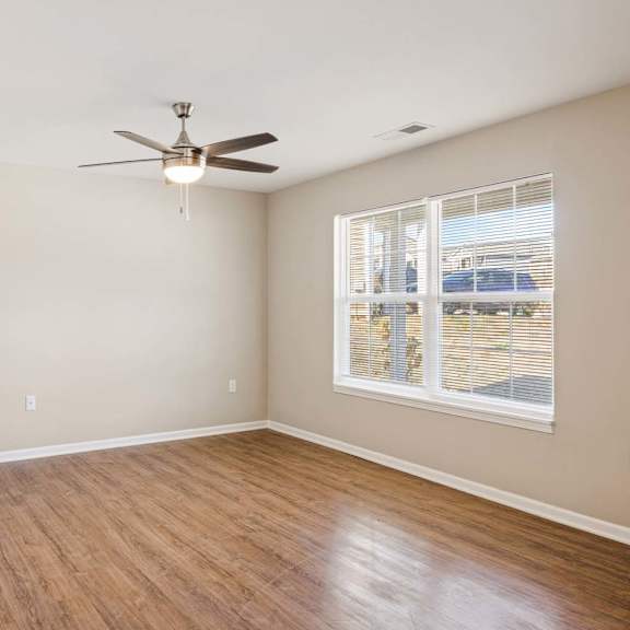 an empty living room with a ceiling fan and a window