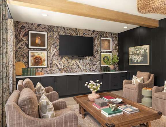 A living room with a brown couch, a coffee table, and a television on the wall.
