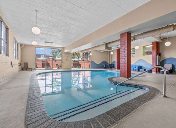 A large indoor swimming pool with a tiled edge and a metal ladder.