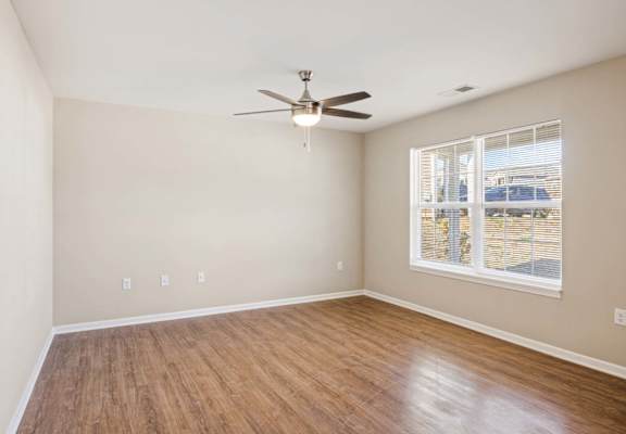 an empty living room with a ceiling fan and a window