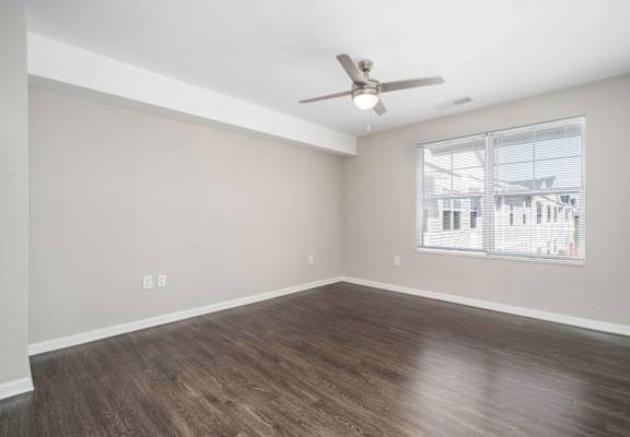 an empty living room with a ceiling fan and a window