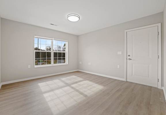 an empty living room with a white door and a window