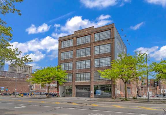a six story brick and glass building on a city street with trees in front of it