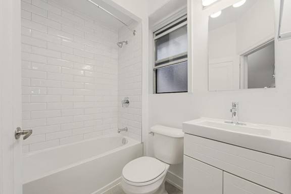 A white bathroom with a toilet, sink, and tub. at 723 Bloor Apartments, Canada, M6G 1L5