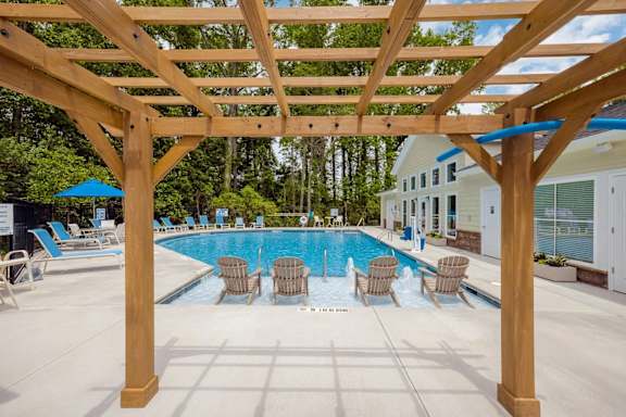 A wooden pergola over a swimming pool with lounge chairs underneath.at Helena Springs, Augusta, GA 30909