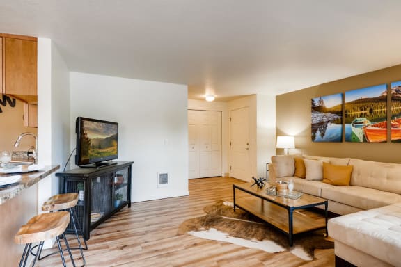 Apartments Near Happy Valley, OR For Rent - Spacious Living Area With Wood-Inspired Flooring, Plenty Of Windows To Let In Natural Sunlight, Front Door, And View Of Kitchen And Dining Area