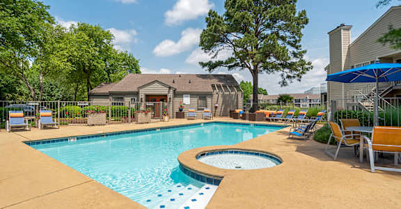A swimming pool surrounded by chairs and trees. at Reflection Pointe, Flowood, MS