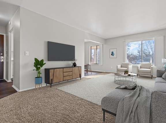 A living room with a grey couch and a television on the wall.