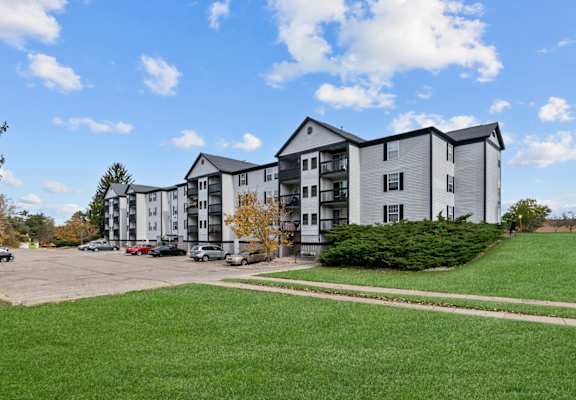 Apartment complex with a parking lot in front.