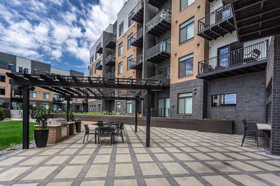 A patio with a table and chairs is surrounded by apartment buildings.