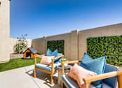 Thumbnail 3 of 5 - A patio with two chairs and a table with a pink pillow and a blue pillow on it.