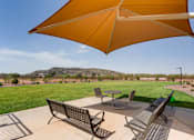 Thumbnail 2 of 5 - A patio with a table and chairs under a large umbrella.