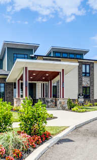 A modern house with a large front yard and a driveway.