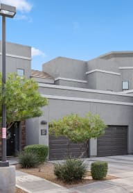 a gray house with two garage doors and a driveway