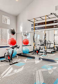 A gym with a treadmill, exercise balls, and weight machines.