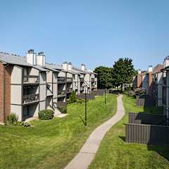 A long pathway leads through a grassy area between apartment buildings.