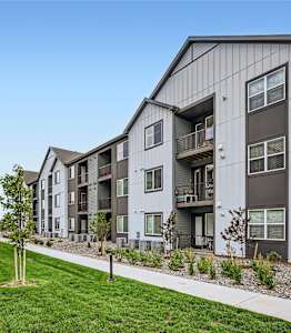 a row of apartment buildings with grass and a sidewalk