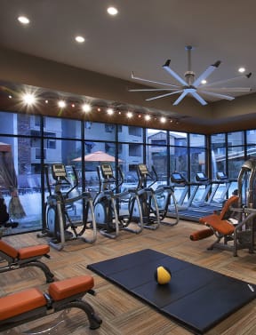a spacious fitness room with cardio equipment and weights