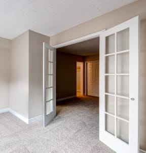 an empty living room with open doors to a hallway