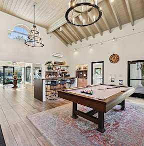 A pool table is in the middle of a room with a wooden floor.