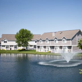 a fountain in the middle of a pond in front of a building