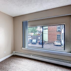an empty bedroom with a large window and a parking lot