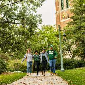 a group of people walking down a sidewalk on a college campus