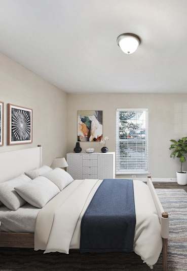 Apartments in Sandy Springs Georgia for Rent – Celebration at Sandy Springs - A bedroom with a bed, nightstand, and a plant.