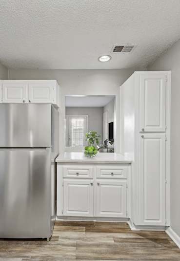 Pet-Friendly Apartments in Sandy Springs– Celebration at Sandy Springs – A kitchen with a refrigerator, cabinets, and a dining table.