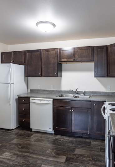A kitchen with a white fridge, black cabinets, and a white stove top oven.