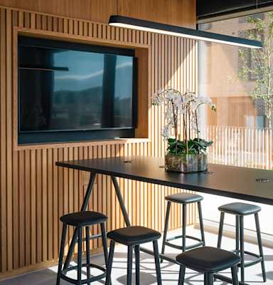 A black table with four stools in front of a wooden wall with a television at Cherrywood Apartments, D18 VY3V, DUBLIN 18
