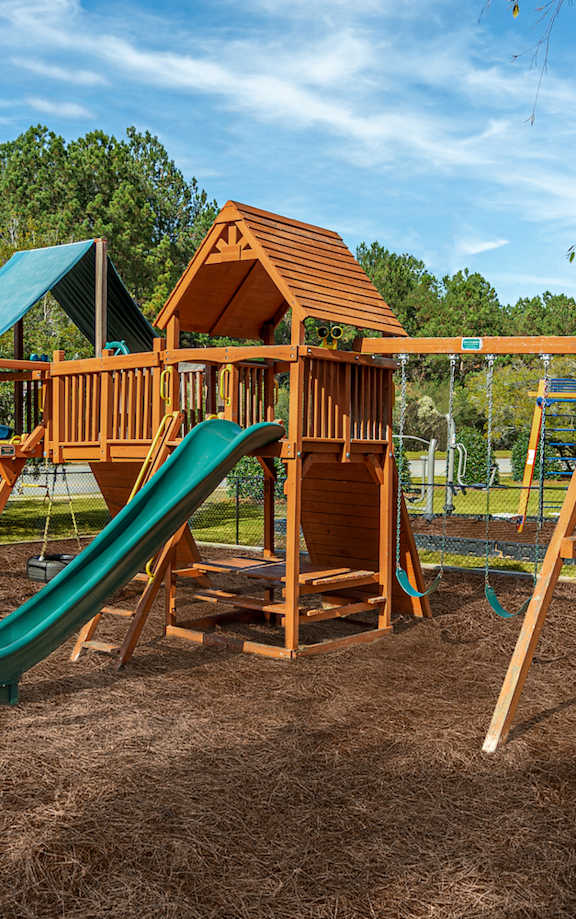 A wooden playground structure with a green slide.