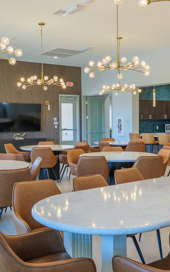 A large room with tables and chairs and a TV.