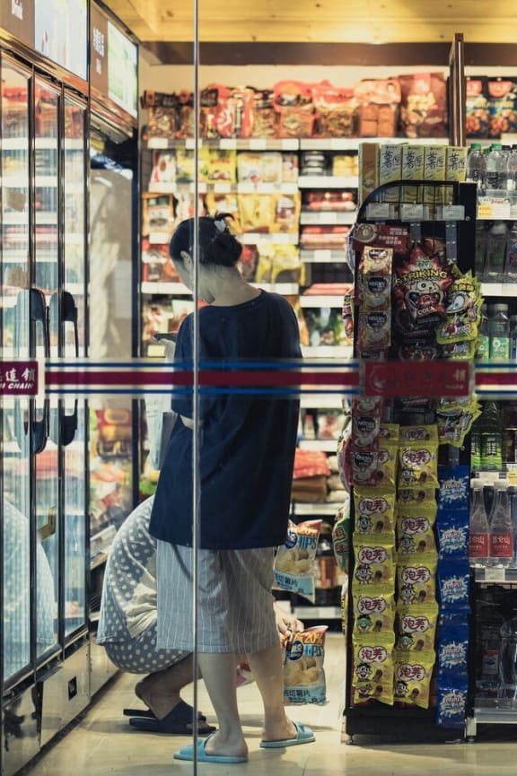 two women standing in front of a refrigerator in a supermarket