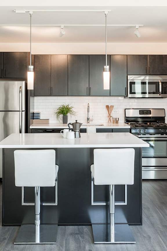 A modern kitchen with a white countertop and black bar stools.